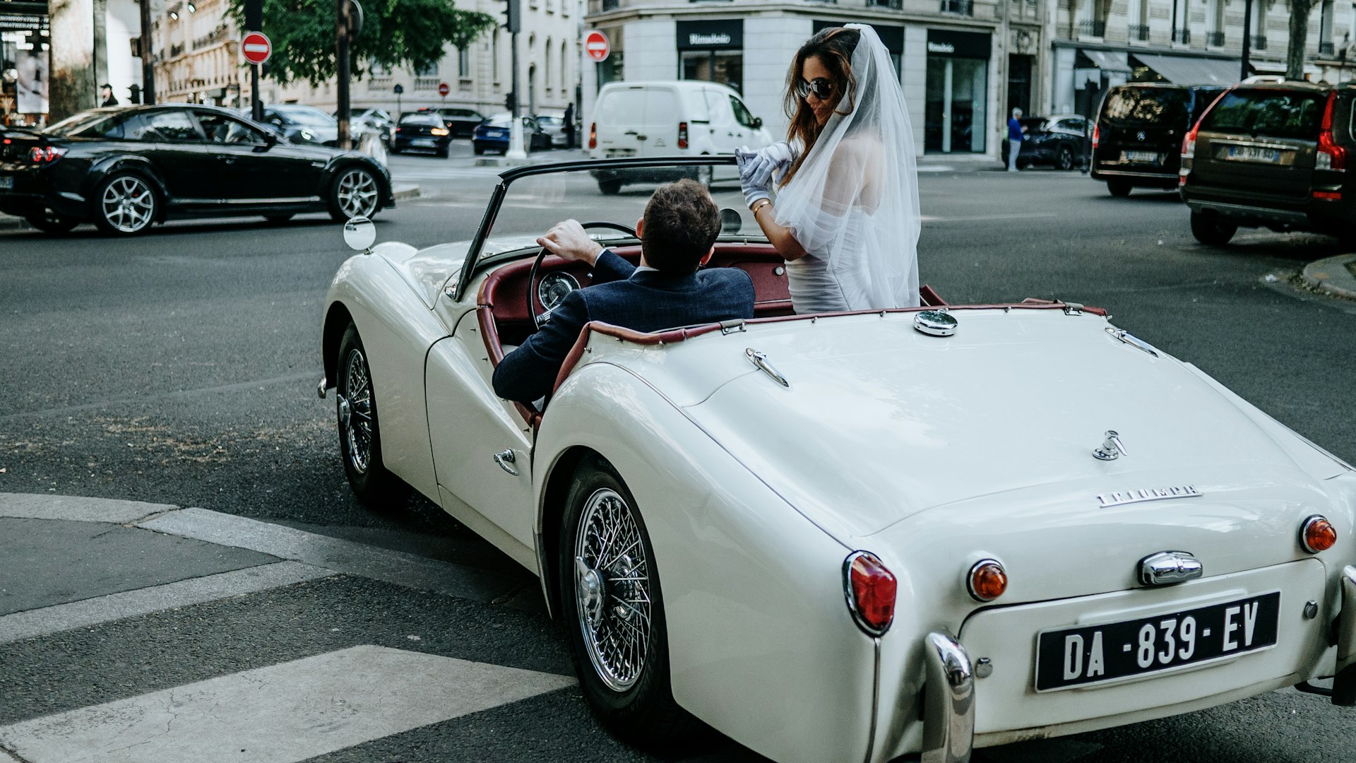 A bride and groom ride in a classic car.